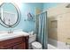 Well-appointed bathroom with turquoise walls, tiled shower, new fixtures, and custom round mirror at 6005 Carlyle Dr, Raleigh, NC 27614