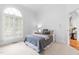 Bright bedroom with large arched window, neutral carpet, and doorway to hallway with hardwood floors at 6005 Carlyle Dr, Raleigh, NC 27614