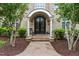 Elegant brick home featuring a stunning arched entryway, ornate double doors, and meticulously landscaped surroundings at 6005 Carlyle Dr, Raleigh, NC 27614