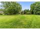 Large front yard with green grass and mature trees in a landscaped setting at 6005 Carlyle Dr, Raleigh, NC 27614