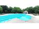 Community swimming pool surrounded by lounge chairs, shade umbrellas, and mature trees in a park-like setting at 6005 Carlyle Dr, Raleigh, NC 27614
