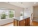 Kitchen area with a large island featuring ample cabinet space, hardwood floors, and natural light from nearby windows and stairway at 615 Carlton Commons Ln, Cary, NC 27519