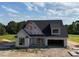Modern design on a two-story home featuring an attached two car garage, black roof and contrasting white siding at 6332 River Rd, Fuquay Varina, NC 27526