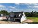 Elegant white home featuring dark window frames and roof situated on a spacious lot surrounded by lush greenery at 6332 River Rd, Fuquay Varina, NC 27526