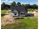 New home in a picturesque setting, featuring dark roof, and open porch on a large lot with scattered trees at 6332 River Rd, Fuquay Varina, NC 27526