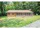 Ranch-style home with wood siding and a screened front porch, nestled in a wooded area at 7030 Stockard Rd, Snow Camp, NC 27349