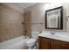 Bathroom featuring neutral colored tile shower-tub, vanity with storage, framed mirror and modern fixtures at 7409 Chesley Ln, Durham, NC 27713