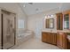 Bright bathroom with a tub, separate shower, and a vanity with wood cabinets at 7409 Chesley Ln, Durham, NC 27713
