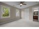 Bright bedroom featuring neutral tones, two windows, a ceiling fan and an attached bathroom entrance at 7409 Chesley Ln, Durham, NC 27713