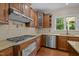 A well-equipped kitchen featuring wood cabinetry, granite countertops, and stainless steel appliances at 7409 Chesley Ln, Durham, NC 27713