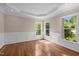 Bright living room with hardwood floors, tray ceiling, decorative trim, and large windows for ample natural light at 7409 Chesley Ln, Durham, NC 27713