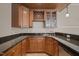 Basement wet bar featuring wood cabinets, black granite countertops, and a stainless-steel dishwasher at 7409 Chesley Ln, Durham, NC 27713