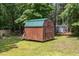 Charming wooden shed with a green metal roof nestled amongst mature trees at 105 Rolling Stone Ct, Sanford, NC 27332