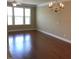 Spacious living room features hardwood floors, a modern chandelier, and large windows providing lots of natural light at 115 Ballyliffen Ln, Cary, NC 27519