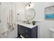 Stylish bathroom featuring a navy blue vanity, round mirror, and neutral color scheme at 1218 Chimney Hill Dr, Apex, NC 27502