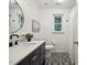 Modern bathroom featuring patterned tile floors, black vanity, round mirror, and window at 1218 Chimney Hill Dr, Apex, NC 27502
