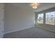 Bright bedroom featuring soft gray carpet, two windows, overhead lighting, and neutral paint at 1227 Bessie Ct, Wake Forest, NC 27587