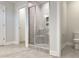 Well-lit bathroom featuring an enclosed tiled shower, toilet, and neutral tile flooring at 13 Knotty Pine Lane, Clayton, NC 27520