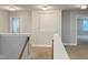 Hallway with neutral walls and carpet with railing and open doorway in a new home at 13 Knotty Pine Lane, Clayton, NC 27520