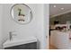 Modern half bath featuring a round mirror and views of the kitchen area at 1314 S East St, Raleigh, NC 27601