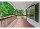 Cozy covered porch with wood flooring and railings, offering a peaceful outdoor space to relax and enjoy the wooded views at 141 S Creek Dr, Louisburg, NC 27549