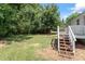 A view of backyard deck with steps leading down to a grassy yard shaded by mature trees at 1941 White Memorial Church Rd, Willow Springs, NC 27592