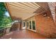 View of a wood deck featuring a retractable awning, brick, and trees at 200 Greensview Dr, Cary, NC 27518