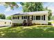 Front of house displaying tidy landscaping, black shutters, wood front stairs, and a manicured lawn at 2112 Mckinney St, Burlington, NC 27217