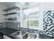 Bright kitchen view showcasing double basin stainless sink, tiled backsplash, stainless shelves and a view to the backyard at 2112 Mckinney St, Burlington, NC 27217