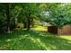 Lush backyard featuring mature trees, a storage shed, and a manicured lawn with views of the home at 2821 Regent Park Ln, Burlington, NC 27217