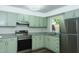 Modern kitchen with stainless steel appliances, light green cabinets, and granite countertops at 2821 Regent Park Ln, Burlington, NC 27217