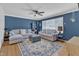 Cozy living room with blue walls, hardwood floors, ceiling fan, and large window for ample natural light at 3509 Crofton Ct, Raleigh, NC 27604