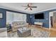 Comfortable living room featuring a large window, ceiling fan, hardwood floors, and blue accent wall at 3509 Crofton Ct, Raleigh, NC 27604