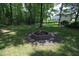 Outdoor fire pit with brick surround in a wooded backyard, perfect for evening gatherings and relaxation at 4601 Basilica Dr, Holly Springs, NC 27540