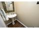 Half bathroom featuring a pedestal sink, decorative mirror, and dark wood flooring at 4601 Basilica Dr, Holly Springs, NC 27540