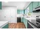 Well-lit kitchen featuring teal cabinetry, white countertops, modern appliances, and ample storage space at 5 Windsor Pl, Mebane, NC 27302