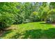 Expansive backyard features a lush green lawn, storage shed, and serene natural surroundings at 7401 Heartland Dr, Wake Forest, NC 27587