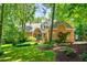 Beautiful brick home with manicured lawn, mature trees, and inviting front porch with an arched entryway at 7401 Heartland Dr, Wake Forest, NC 27587