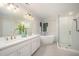 Bright bathroom featuring double sinks, a glass shower, and a white soaking tub at 7605 Sandy Lake Ct, Raleigh, NC 27613
