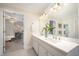 Bright bathroom featuring double vanity, quartz countertop, stylish light fixture, and doorway to a room with modern decor at 7605 Sandy Lake Ct, Raleigh, NC 27613
