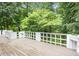 Wooden deck features white railings and a view of the surrounding trees and greenery at 7605 Sandy Lake Ct, Raleigh, NC 27613