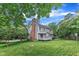 Back exterior featuring brick chimney, deck, and well-maintained lawn at 8121 Bentwood Pl, Raleigh, NC 27615