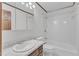 White tiled bathroom with marble countertop sink and wood cabinets at 8121 Bentwood Pl, Raleigh, NC 27615