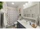 Well-lit bathroom featuring a navy blue vanity, decorative mirror and a shower with a floral curtain at 817 Mossy Oak Dr, Fuquay Varina, NC 27526