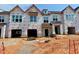 New construction townhomes with garage and covered doorway with unfinished landscaping on a sunny day at 91 Ripple Way # 213, Clayton, NC 27520