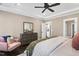 Bright main bedroom featuring a tray ceiling, ceiling fan, a wood dresser, and a comfortable pink chair at 1119 Brookfield Dr, Gibsonville, NC 27249