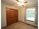 Bedroom with light-filled window, neutral carpet, and closet with wood doors and overhead ceiling fan at 116 Trinity Woods Dr, Raleigh, NC 27607