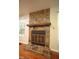 Close up of a stone fireplace with a wooden mantle and hearth, flanked by windows at 116 Trinity Woods Dr, Raleigh, NC 27607