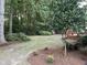 Expansive backyard featuring mature trees, a manicured lawn, and a wooden deck ideal for relaxation and enjoyment at 1210 Eastham Dr, Apex, NC 27502