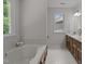 Bright bathroom with a soaking tub, double vanity, and a window offering natural light and view at 1210 Eastham Dr, Apex, NC 27502
